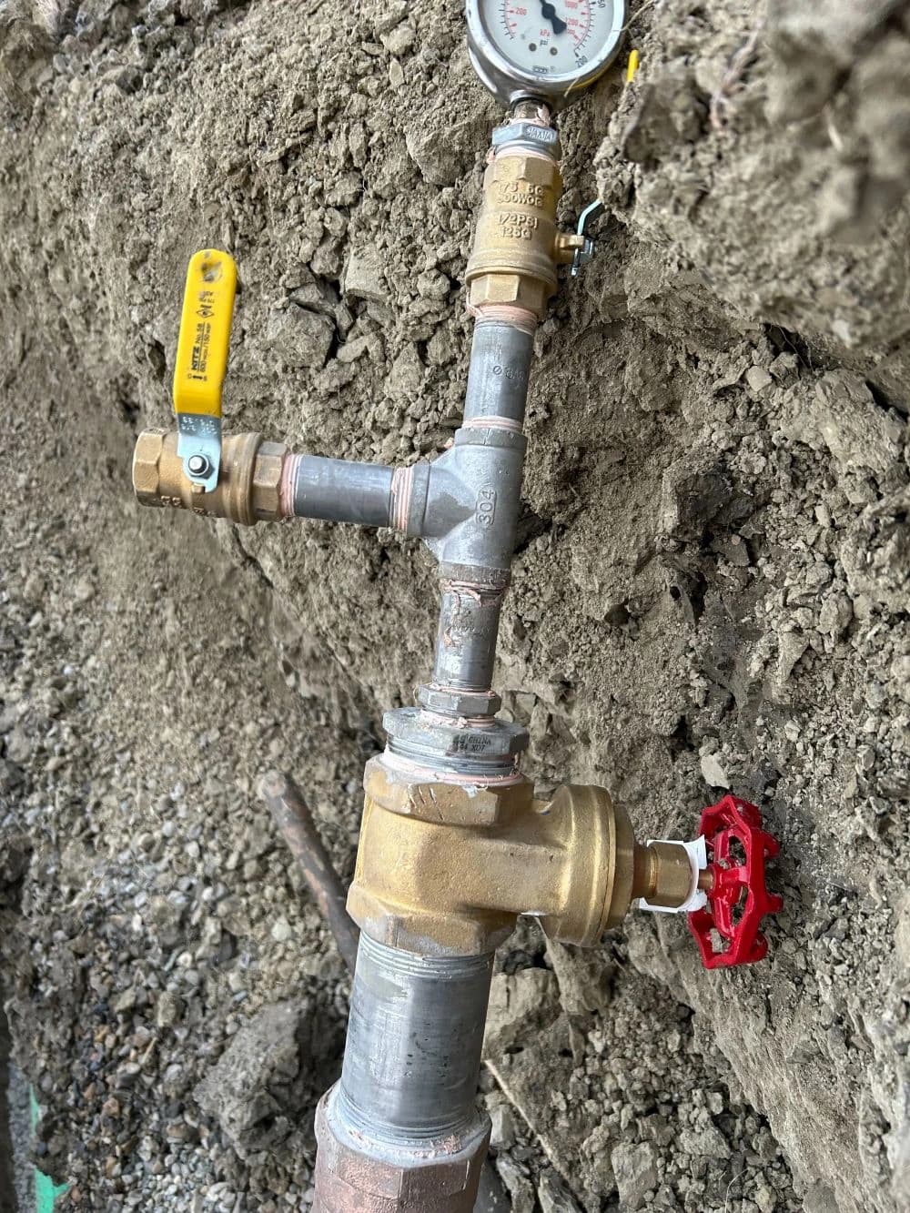 Buried gas-line pressure-test assembly with gauge and shut-off valves in an open trench